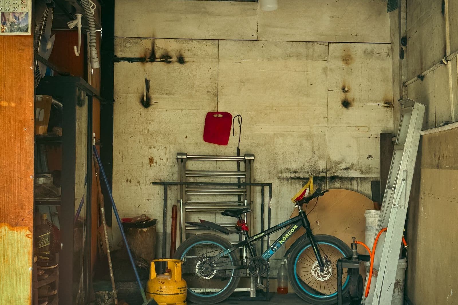 A lived-in residential garage with an oil-stained concrete floor, bicycle and tools